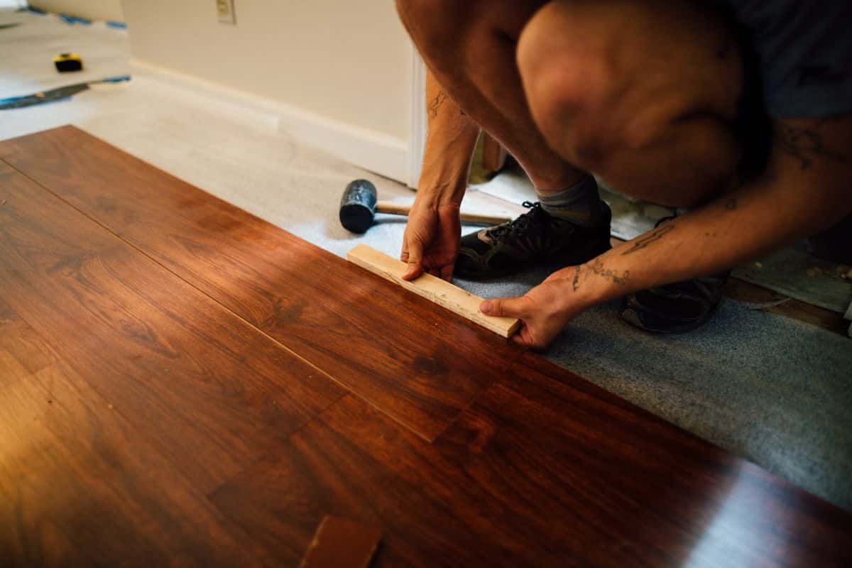 Hands laying laminate flooring planks