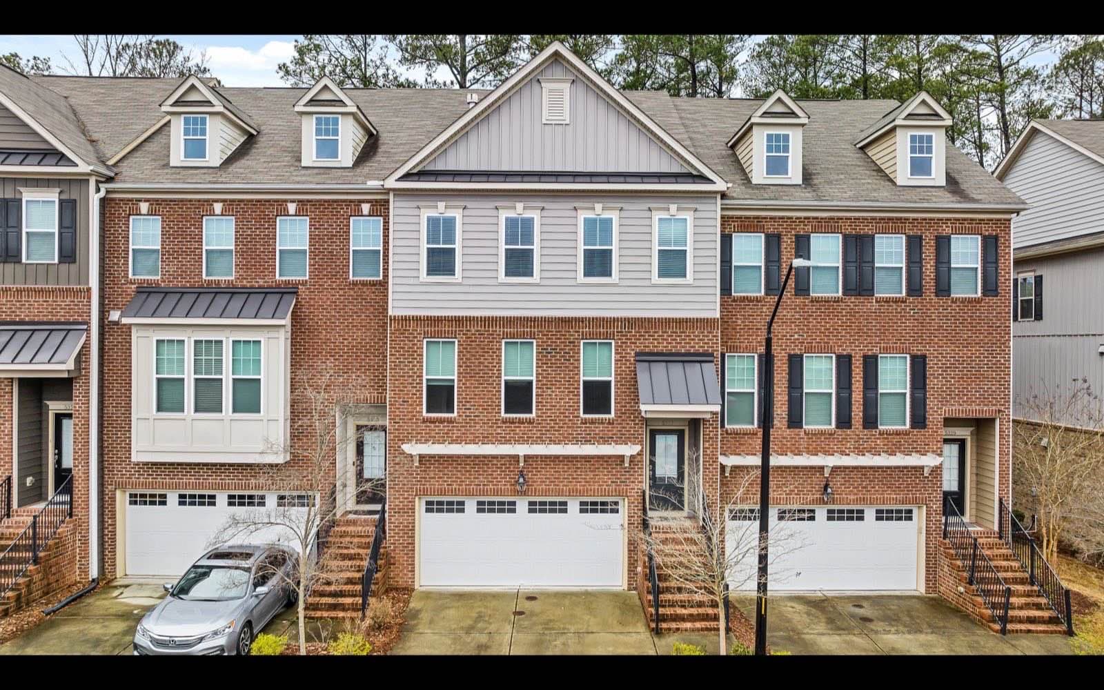 A row of brick townhouses with garages and trees