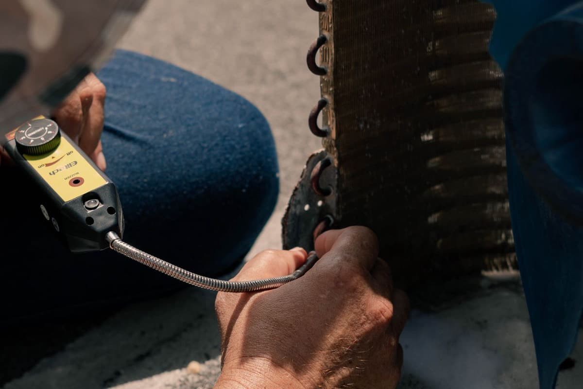 A technician servicing a wall-mounted air conditioner