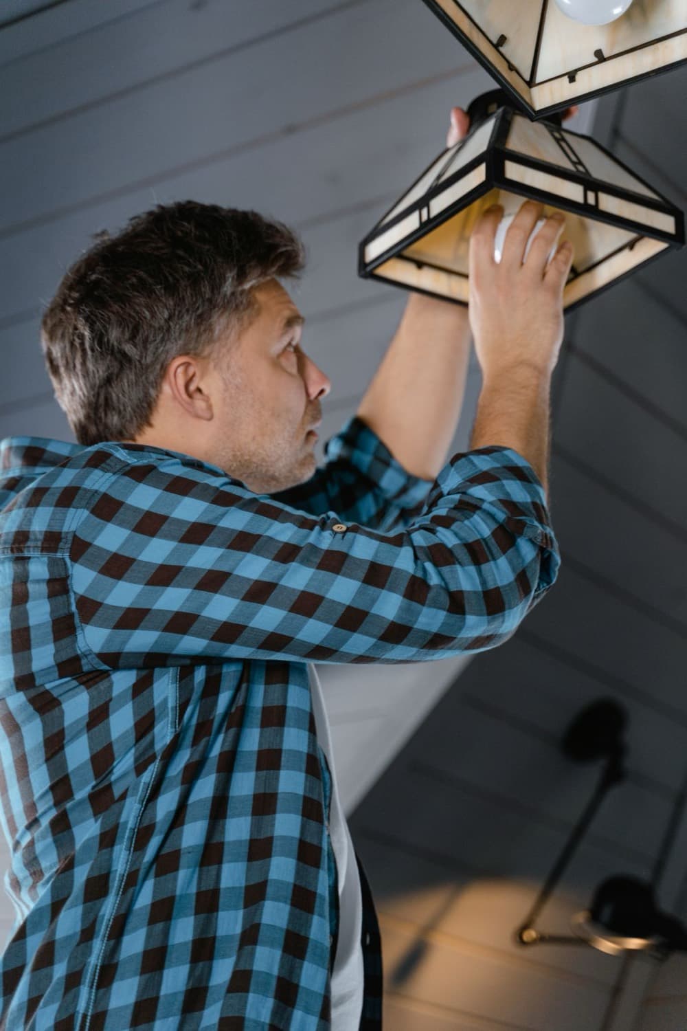 A Handymaen technician installing a ceiling light fixture in a customer's home