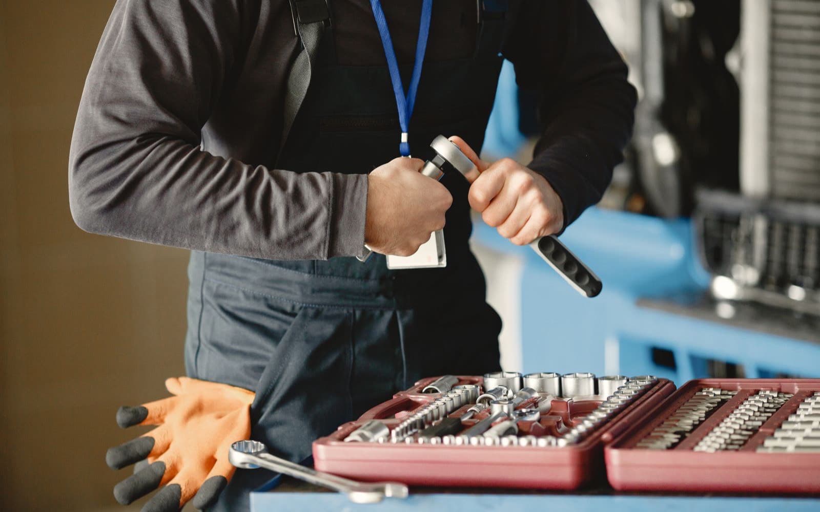 A technician in overalls choosing a wrench from an open toolbox