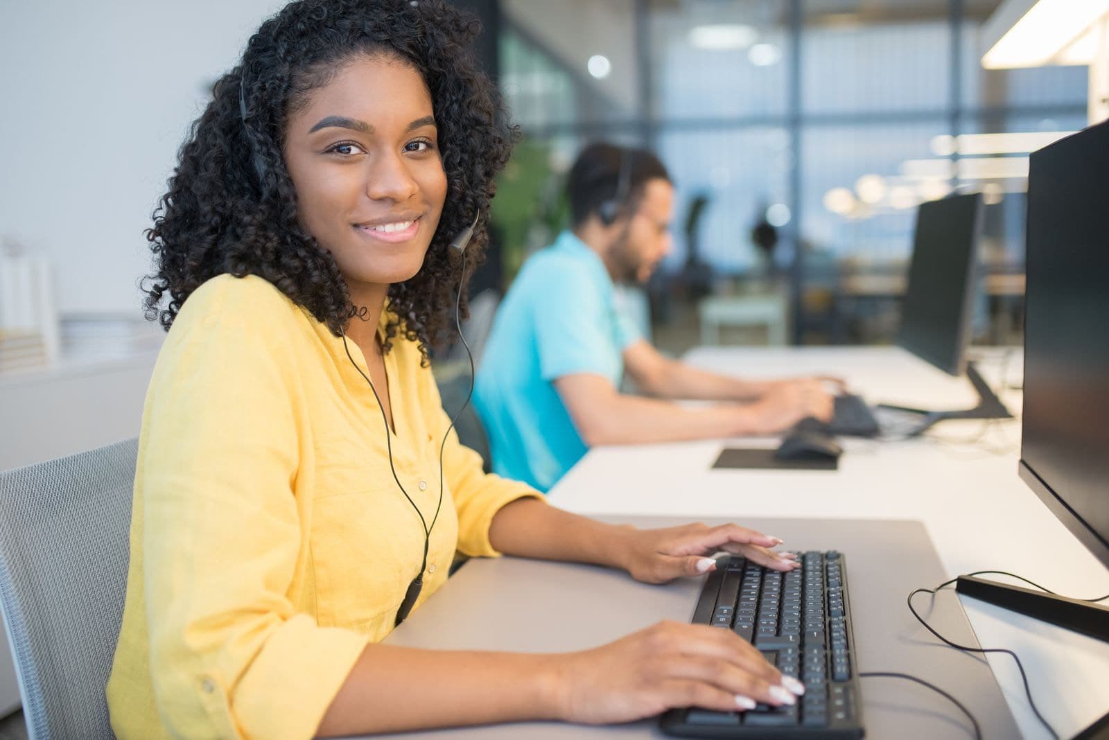 A smiling office coordinator wearing a headset at a computer