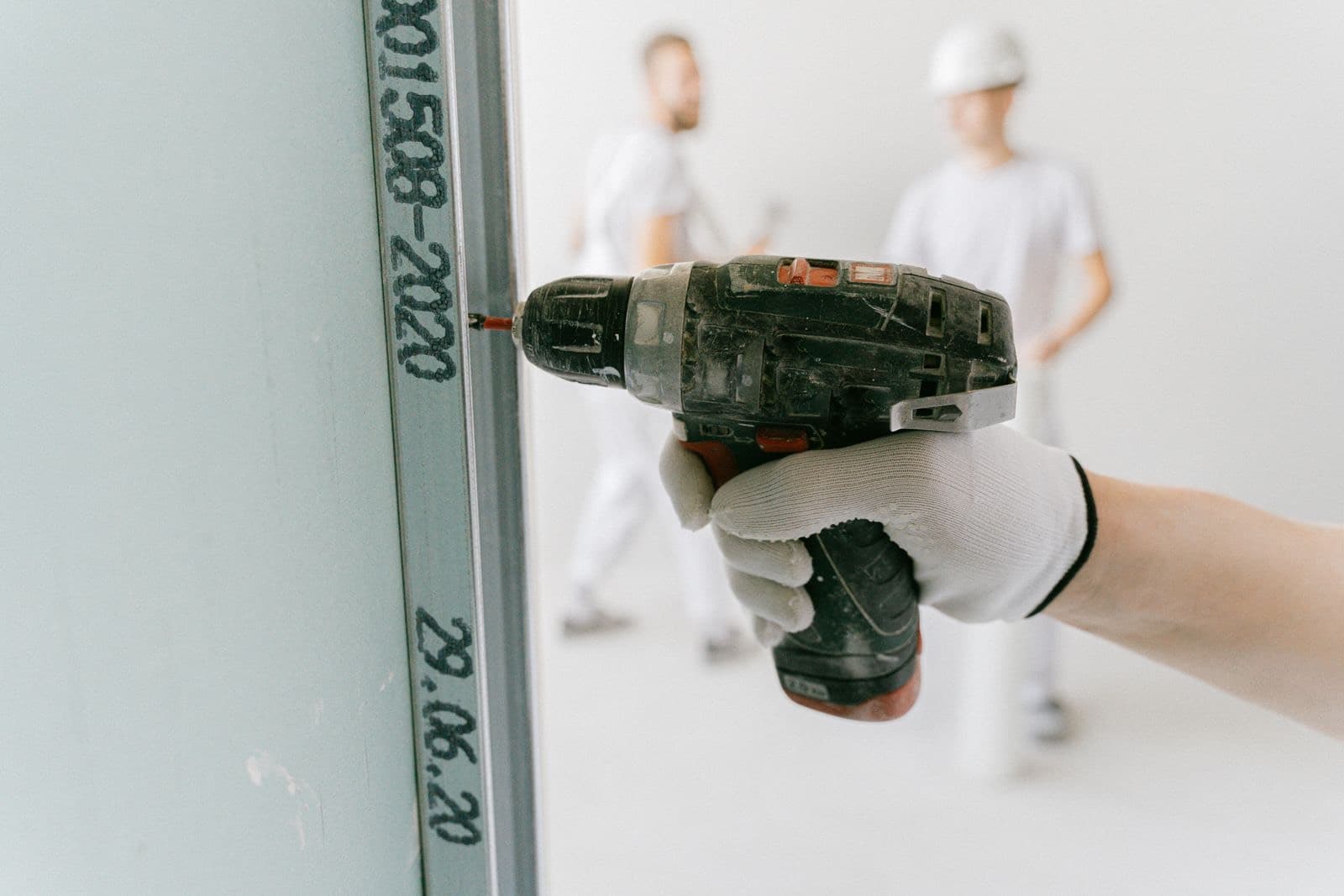 A technician driving a screw into drywall